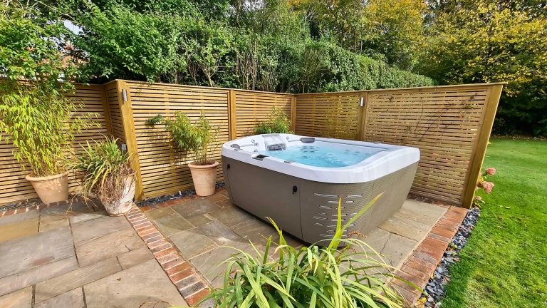 Outdoor jacuzzi enclosed by tall plants, providing privacy while maintaining an open garden feel.
